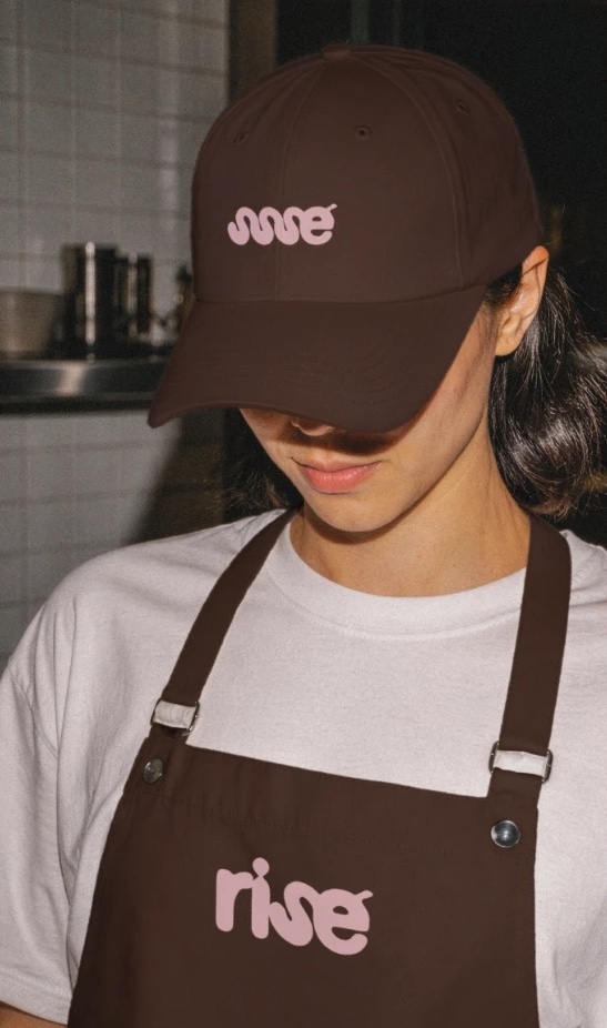 A barista wearing a brown rise cap and apron