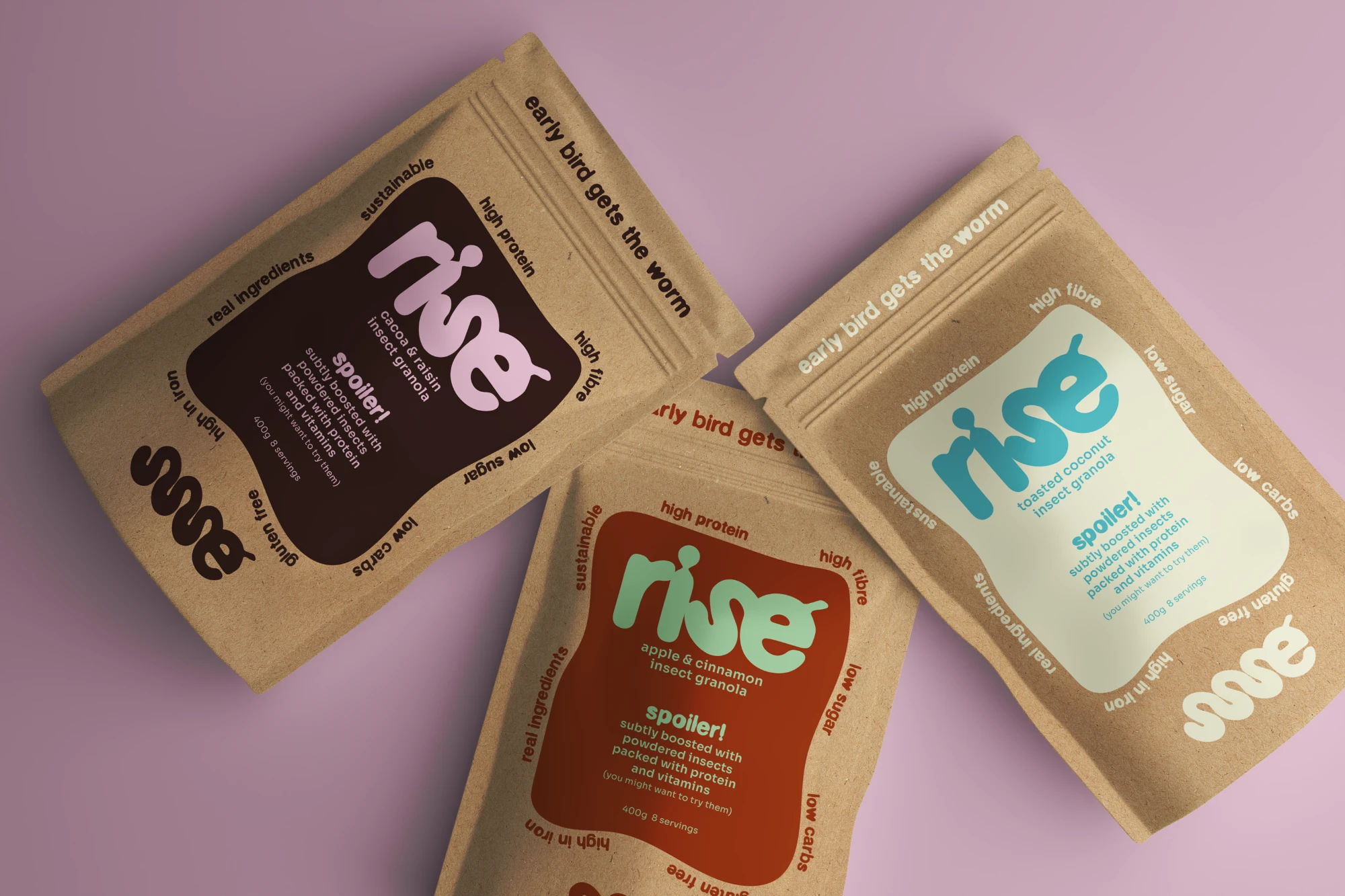 Three rise granola pouches in cacao, apple and coconut flavours on a pink background